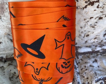 Fita de Halloween Laranja e Preta com Fantasma, Abóbora de Halloween, Chapéu de Bruxa e Vassoura. Cetim de um lado só. 5 jardas (4,57 m) de largura. Fabricada nos EUA.