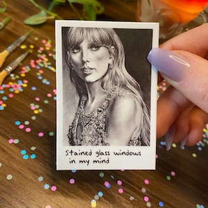 May include: A black and white drawing of a woman with long hair, wearing a sparkly dress. The image is printed on a white card with the text "Stained glass windows in my mind" written below the drawing.