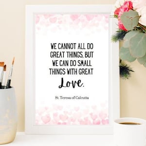 Puede incluir: Una impresión enmarcada blanca con un fondo rosa y blanco de corazones. La impresión presenta una cita de la Madre Teresa: "No todos podemos hacer grandes cosas, pero podemos hacer pequeñas cosas con gran amor."