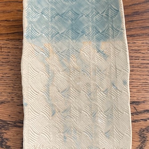 Könnte beinhalten: Eine rechteckige Keramikschale mit einem blauen und weißen Chevron-Muster. Die Schale hat eine strukturierte Oberfläche und ist mit "Kac 3/21" und "C. Smith" signiert.