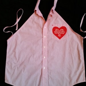 May include: A pink and white striped shirt with a red heart-shaped patch that says "This is a shirt that I used to wear. Whenever you cook in it know that I am near. Love, Papa."