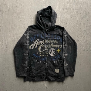 Może przedstawiać: Czarna bluza z kapturem zapinana na zamek z napisem Affliction American Customs, Brooklyn Royal oraz Built For Speed. Odzież posiada okrągłą grafikę 73 z żółtym krzyżem, ozdobne wzory krzyży na rękawach oraz okrągłą naszywkę.