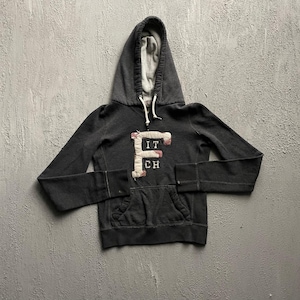 May include: A charcoal gray long-sleeve hooded sweatshirt featuring a large, cream-colored fabric applique letter F with the letters IT and CH stacked below it. The hoodie includes a front kangaroo pocket and white drawstring cords at the neck.