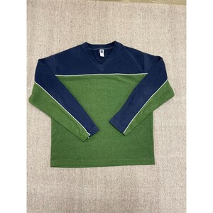 Pode incluir: Uma camisola de manga comprida com blocos de cor em azul marinho e verde. A parte superior é azul marinho, a inferior é verde e uma faixa branca acentua as mangas. A camisola tem decote em V e o logótipo Gap.