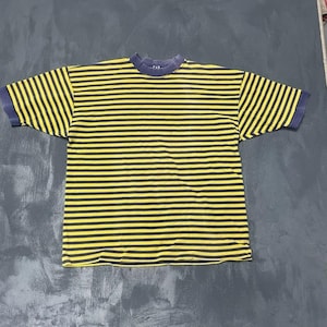 May include: A short-sleeved t-shirt featuring a horizontal striped pattern in yellow and dark navy blue. The garment has a solid dark navy blue crew neckline and matching sleeve cuffs. The brand name GAP is visible on the inner neck label.