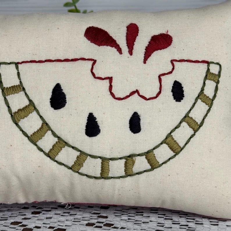 Rectangle mini pillow  6"x10" embroidered on natural muslin with "one in a melon" in black floss and a watermelon in red, two shades of green for the rind and black seeds. Backed with red ticking stipe cotton.
