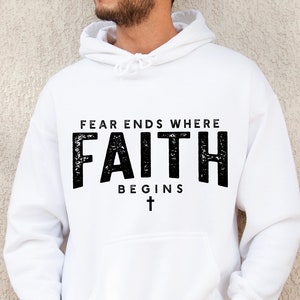 May include: White hooded sweatshirt with the text "FEAR ENDS WHERE FAITH BEGINS" and a small cross below the text.