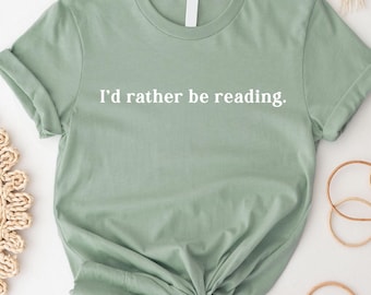 May include: A sage green t-shirt with the text "I'd rather be reading." printed in white.