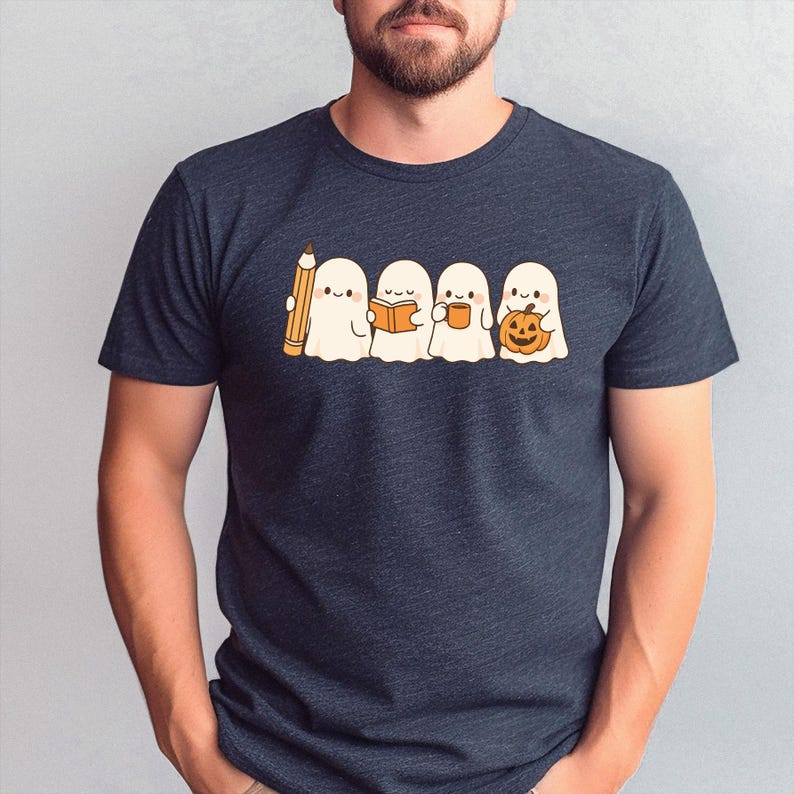 May include: Dark navy blue t-shirt featuring a cute cartoon of four ghosts. One ghost holds a pencil, another a book, the third a mug, and the last a pumpkin. The ghosts are white with black eyes and are smiling.