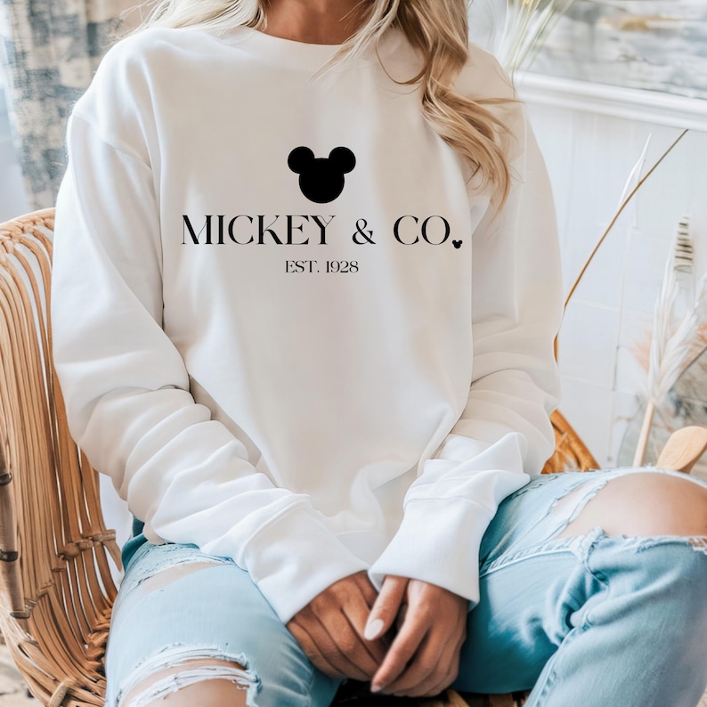 May include: White sweatshirt with a black Mickey Mouse head and the text "Mickey & Co. Est. 1928" printed on the front.