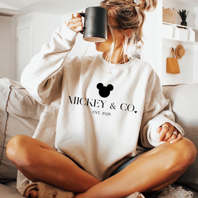 May include: A white sweatshirt with a black Mickey Mouse head and the text "Mickey & Co. Est. 1928" printed on the front.