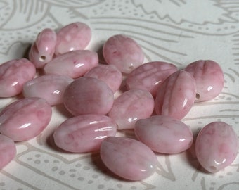 May include: A collection of oval-shaped pink beads with a glossy finish. The beads have a marbled appearance with streaks of white and pink.