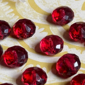 以下が含まれることがあります： 赤いファセットカットガラスビーズのグループ。ビーズは丸く、光沢のある仕上げになっています。