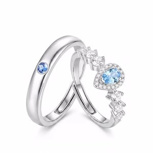 Peut inclure: Une paire de bagues argentées. L'une présente une pierre bleue ronde sertie sur un anneau lisse. L'autre bague arbore une pierre bleue en forme de poire entourée d'un halo de petites pierres claires, avec d'autres pierres claires sur l'anneau.