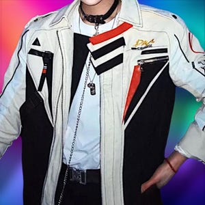 Puede incluir: Chaqueta blanca y negra con detalles rojos y cierre de cremallera. La chaqueta tiene cuello y un diseño en el pecho. Se lleva con una camisa blanca y un collar de gargantilla negro.