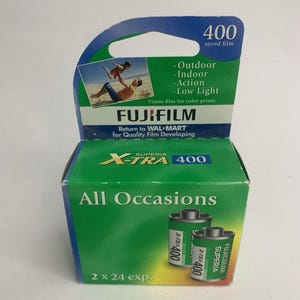 May include: A green and blue Fujifilm Superia X-TRA 400 film box. The box features the text "All Occasions" and "2 x 24 exp." The box also includes a photo of a person and child on a beach. The film is 35mm.