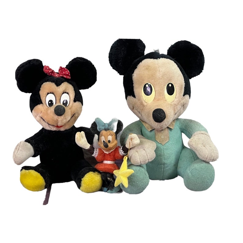 May include: Three plush Mickey Mouse toys. A black and red Mickey Mouse, a blue and white Mickey Mouse, and a smaller red and white Minnie Mouse.