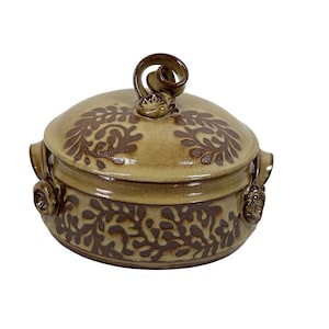 Op de afbeelding: Een bruine en beige keramische ovenschaal met een deksel. De schaal heeft een bloemmotief en een knop op het deksel.