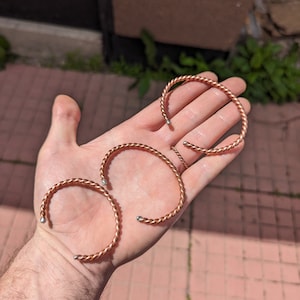 Peut inclure: Quatre bracelets en cuivre avec des accents argentés. Les bracelets sont torsadés et ont une forme arrondie.