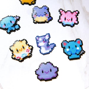 May include: A collection of small pixel art figures crafted from colorful plastic fuse beads. The set includes various creatures in shades of blue, yellow, pink, and purple, each outlined in black, featuring simple facial expressions and distinct shapes.