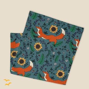 May include: A teal blue fabric face mask with a repeating pattern of orange foxes, yellow sunflowers, and green leaves.