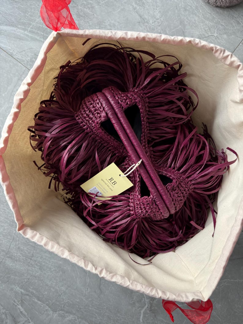 May include: A deep burgundy woven handbag with long, flowing fringe detailing, featuring two integrated handles and a light yellow rectangular tag attached with a string that displays the text RB special for you and a small QR code.