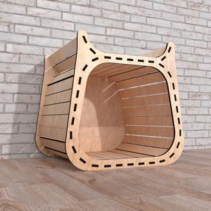 May include: A light-colored wooden storage cube with a curved front and a slatted design. The edges are outlined with a dashed black line. The cube is set against a brick wall and wooden floor.
