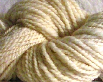 May include: A skein of soft, cream-colored yarn. The yarn is made of natural fibers and has a slightly textured appearance.