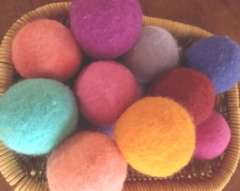 May include: A basket filled with colorful felt balls in various shades of pink, purple, blue, orange, and green. The balls are soft and fluffy, perfect for sensory play or decoration.