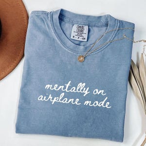 Comfort Colors 1717 t-shirt with the text “Mentally on Airplane Mode”, minimal travel-themed design. Funny airplane mode shirt for travel lovers, airport outfits, vacations, flights, introverts, and everyday casual wear.