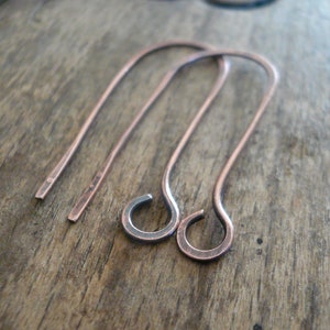 May include: A pair of copper wire earring hooks. The hooks are bent into a simple, rounded shape.