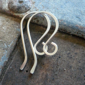 May include: A pair of silver earring hooks. The hooks are made of a smooth, shiny metal and have a simple, elegant design.