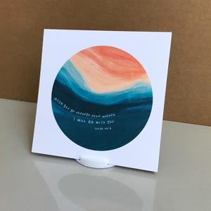 May include: A white card with a circular watercolour design in shades of blue, orange, and peach. The card features the text "when you go through deep waters I WILL BE WITH YOU Isaiah 43:2."