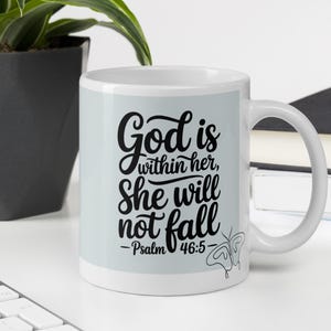 Può includere: Tazza in ceramica bianca con la scritta "God is within her, She will not fall - Psalm 46:5" in corsivo nero. Una grafica a farfalla è sul lato destro della tazza. La tazza è su una superficie bianca.