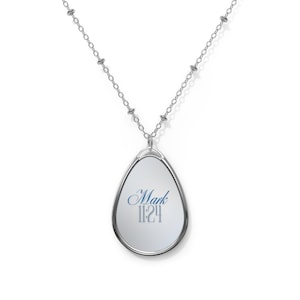 Può includere: Collana con pendente color argento con un pendente ovale. Il pendente ha uno sfondo bianco con le parole "Mark 11:24" in blu. La catena della collana è di colore argento.