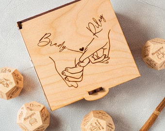 May include: A wooden box with the names "Brady" and "Riley" engraved on the lid. The box contains four wooden dice with different designs, including a heart, a food theme, and a "Date Night" theme.