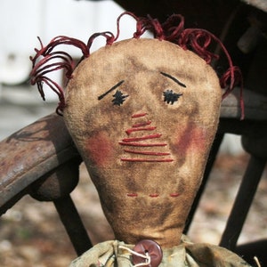 May include: A handmade rag doll with a brown face, red yarn hair, and a simple green and yellow dress. The doll has embroidered eyes and a stitched mouth.