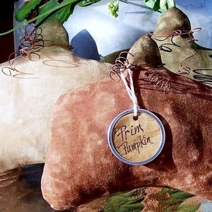 May include: Three handmade fabric pumpkins in beige, brown, and green with wire accents. The brown pumpkin has a tag that reads "Prim Pumpkin".