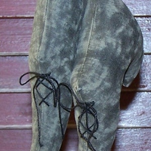Puede incluir: Un par de zapatos de tela gris con cordones negros. Los zapatos son puntiagudos y tienen una forma única.