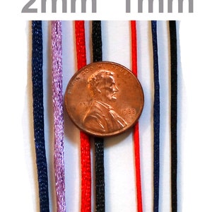May include: A close-up of eight different colored cords, ranging in thickness from 1 mm to 2 mm. The cords are arranged vertically and are next to a US penny for scale.