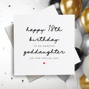 May include: A white card with black text that reads "happy 18th birthday to an amazing goddaughter on her special day". A small red heart is at the bottom of the card.