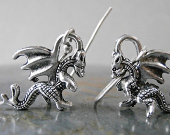 Peut inclure: Une paire de boucles d'oreilles en argent en forme de dragon avec un design détaillé. Les dragons ont des ailes, des écailles et une queue enroulée. Les boucles d'oreilles sont en métal et ont une fermeture à crochet.