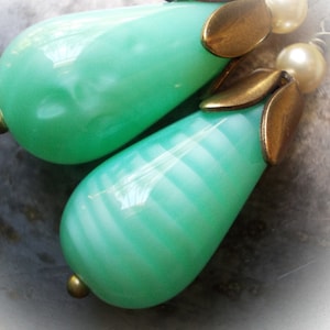 May include: A pair of green glass teardrop earrings with gold accents and white pearl beads.