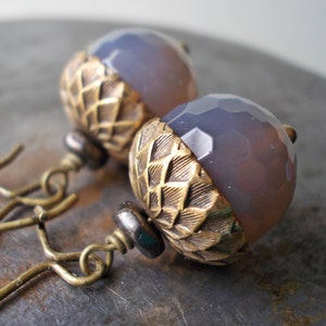 May include: A pair of earrings with a purple agate stone and a brass acorn design.