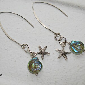 May include: A pair of silver dangle earrings with iridescent green and blue shell and starfish charms.