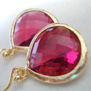May include: A pair of gold earrings with teardrop-shaped red gemstone accents.