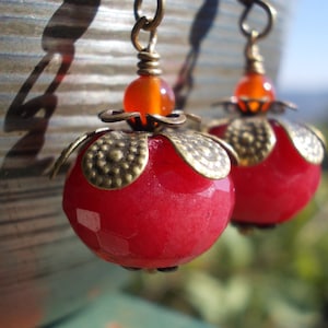 May include: A pair of earrings with red and orange gemstone beads and gold-toned metal accents.
