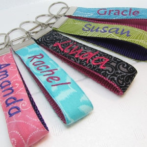 May include: Five personalized keychains with different colored fabric and embroidered names: Amanda, Rachel, Linda, Susan, and Gracie.