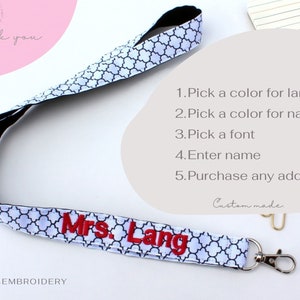 Puede incluir: Lanyard blanco con un patr&oacute;n geom&eacute;trico negro y un nombre bordado en rojo "Mrs. Lang". El lanyard tiene un cierre de seguridad negro y un gancho de metal plateado. La imagen incluye instrucciones para personalizar el lanyard: "1. Elige un color para el lanyard 2. Elige un color para el nombre 3. Elige una fuente 4. Ingresa el nombre 5. Compra cualquier complemento adicional".