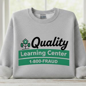 Könnte beinhalten: Ein hellgraues Sweatshirt mit dem Text "Quality Learning Center" in Schwarz und Grün. Das Sweatshirt hat auch die Telefonnummer "1-800-FRAUD" in weißem Text auf einem grünen Balken.